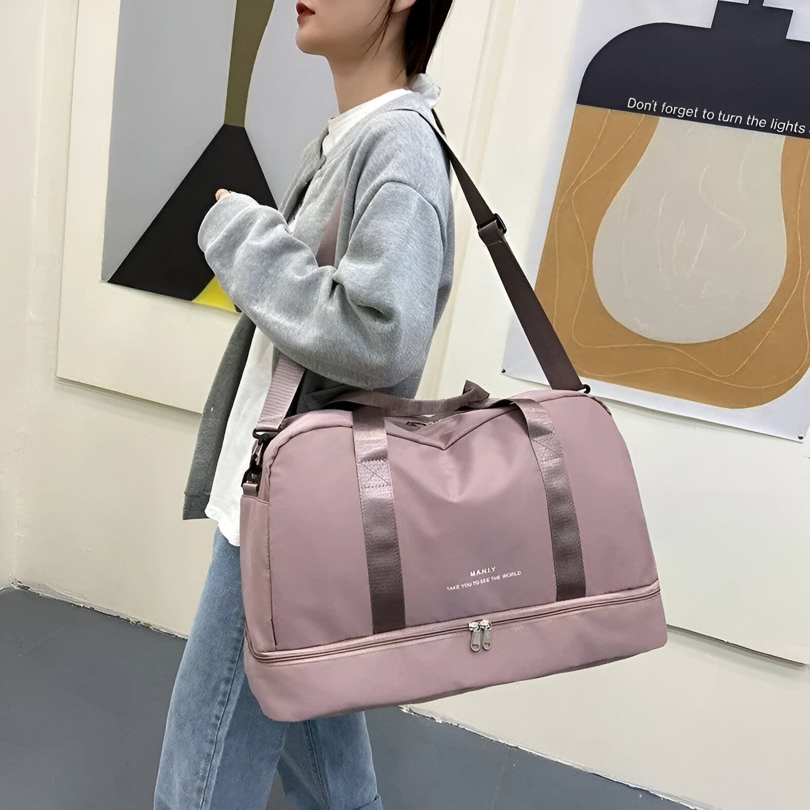 Une femme porte un sac de sport rose avec une bandoulière. Le sac a une fermeture éclair et le logo "MANILY" est imprimé sur le devant.