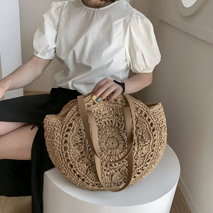 Grand sac cabas rond en paille tressée avec anses beiges, tenu par une femme., 46194029756640,46194029789408