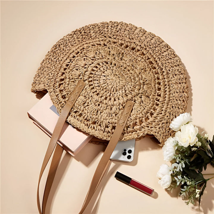 Sac rond en paille rempli d'un livre, d'un smartphone et d'un rouge à lèvres, avec des fleurs blanches à côté., 46194029756640,46194029789408