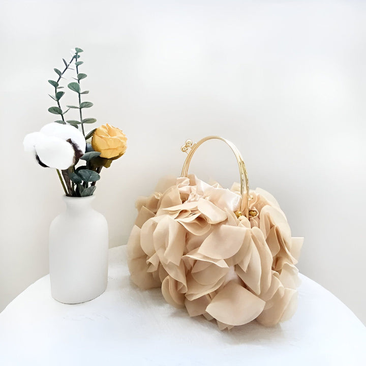 Sac pochette beige avec texture florale et anse dorée, près d'un vase de fleurs., 46193932239072,46193932271840,46193932304608,46193932337376