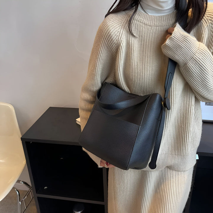 Personne portant un pull côtelé beige, une jupe plissée et un sac à main noir en cuir grainé., 46193878270176,46193878302944,46193878335712,46193878368480