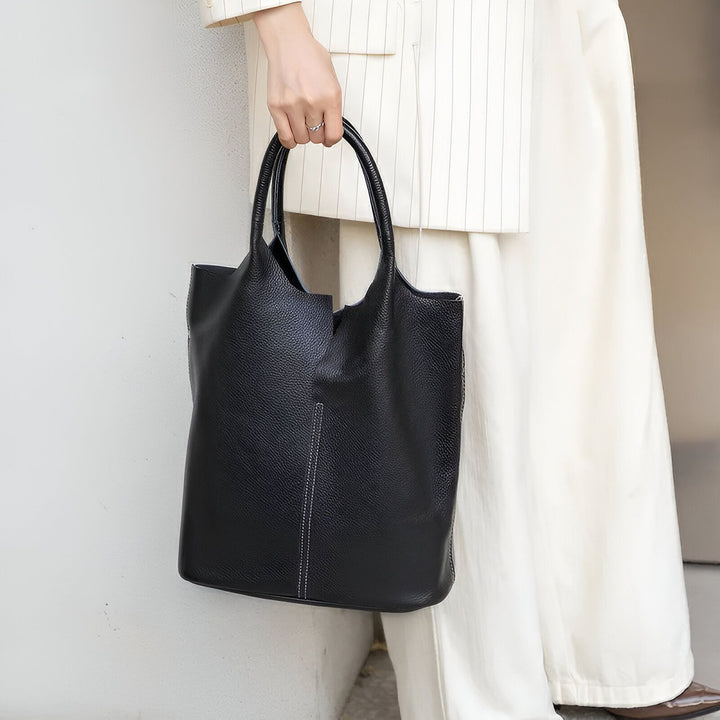 Femme tenant un sac fourre-tout en cuir noir avec couture blanche., 46193872404704,46193872437472,46193872470240,46193872503008,46193872535776