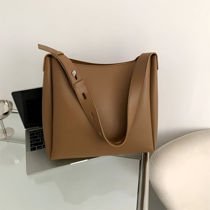 Sac à main en cuir marron posé sur une table près d'un ordinateur., 46193879515360,46193879548128,46193879580896,46193879613664,46193879646432