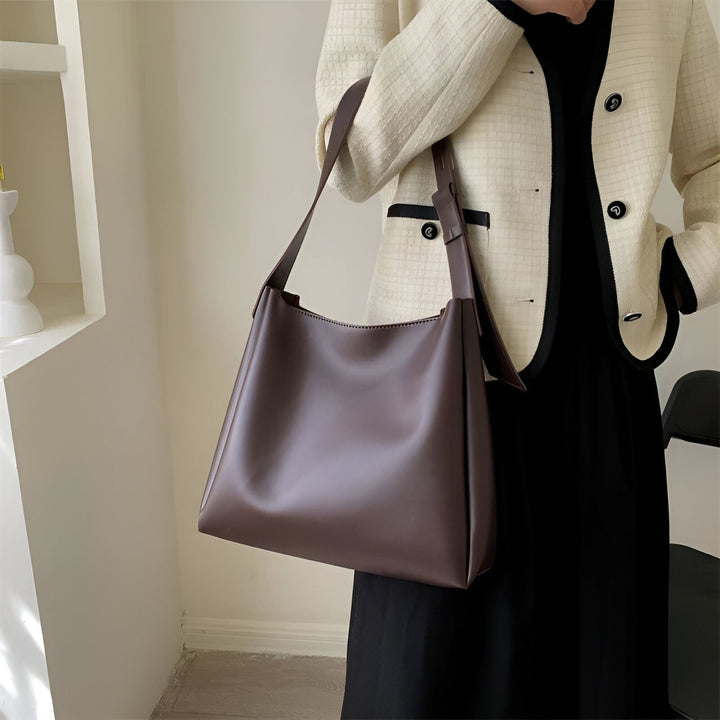 Sac à bandoulière en cuir marron porté par une femme en veste crème., 46193879515360,46193879548128,46193879580896,46193879613664,46193879646432