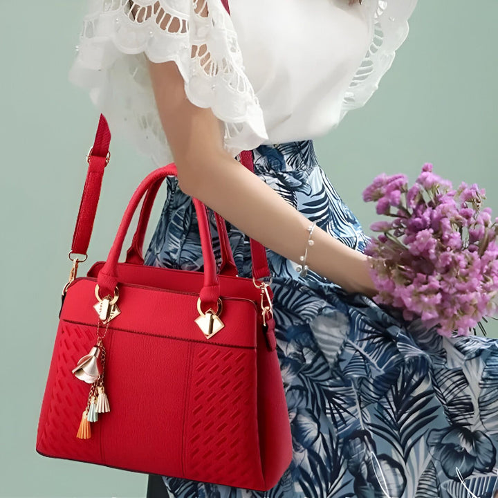 Sac à main rouge porté par une femme en jupe à motifs avec des fleurs., 46193874075872,46193874108640,46193874141408,46193874174176,46193874206944,46193874239712