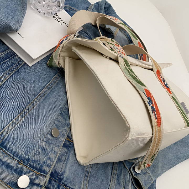 Sac cabas blanc avec bretelles décorées posé sur une veste en jean., 46193894555872,46193894588640,46193894621408,46193894654176,46193894686944