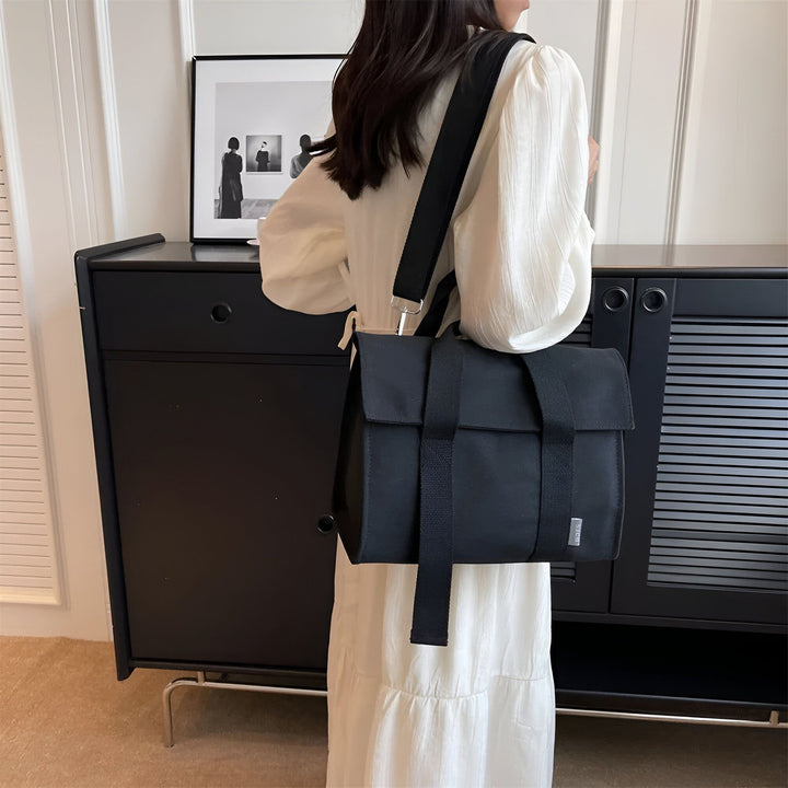 Sac messenger noir porté par une femme en robe blanche., 46193894555872,46193894588640,46193894621408,46193894654176,46193894686944
