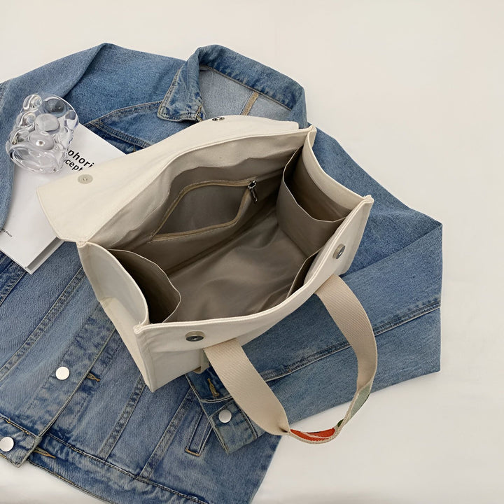 Sac cabas en toile crème ouvert posé sur une veste en jean., 46193894555872,46193894588640,46193894621408,46193894654176,46193894686944