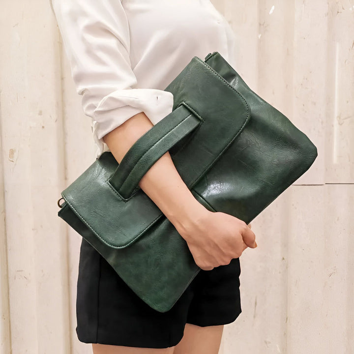 Pochette verte en similicuir tenue sous le bras par une personne., 46194020417760,46194020450528,46194020483296,46194020516064