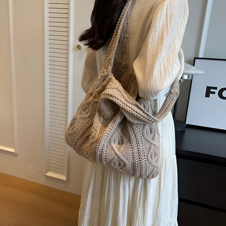 Sac cabas en maille beige avec motif torsadé porté sur l'épaule par une personne en robe longue blanche., 46193946886368,46193946919136,46193946951904,46193946984672,46193947017440
