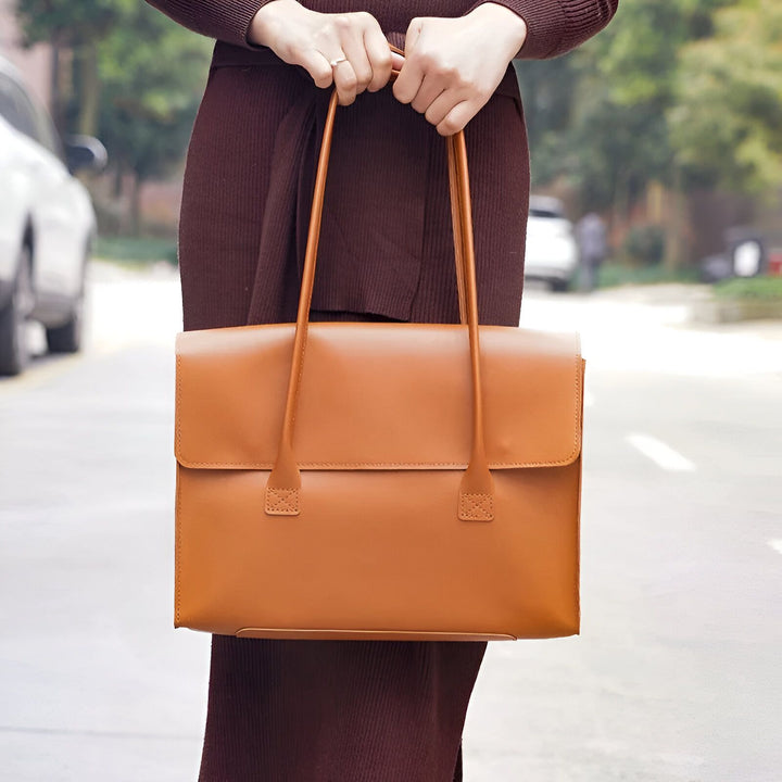 Sac fourre-tout en cuir couleur cognac porté à la main dans la rue., 46193950654688,46193950687456,46193950720224,46193950752992,46193950785760,46193950818528,46193950851296,46193950884064,46193950916832,46193950949600,46193950982368,46193951015136
