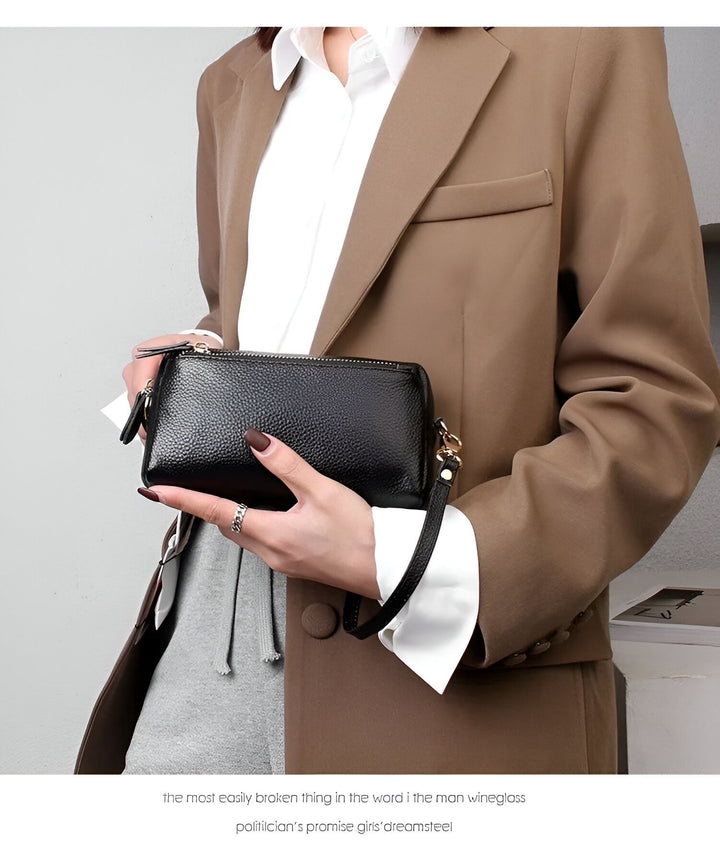 Femme tenant une pochette noire en cuir grainé avec dragonne., 46266441924832,46266441957600,46266441990368