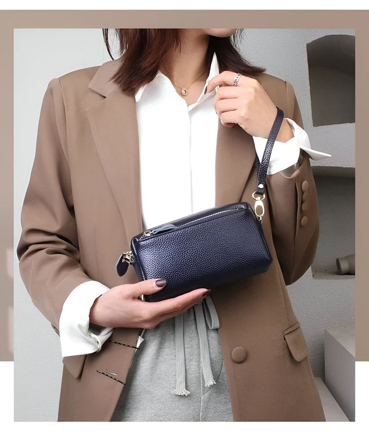 Femme tenant une pochette en cuir bleu marine avec dragonne., 46266441924832,46266441957600,46266441990368