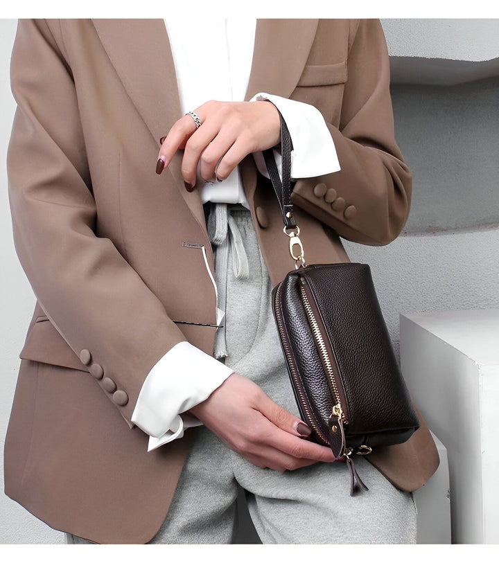 Pochette en cuir grainé marron foncé avec zip doré et dragonne tenue à la main., 46266441924832,46266441957600,46266441990368