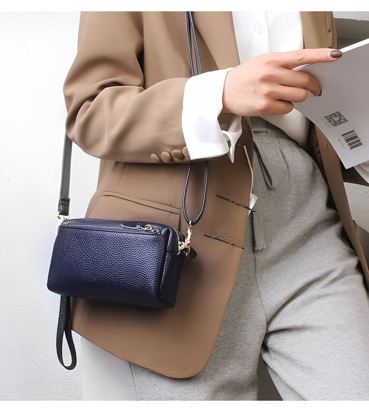 Sac bandoulière en cuir bleu marine porté avec un blazer marron., 46266441924832,46266441957600,46266441990368