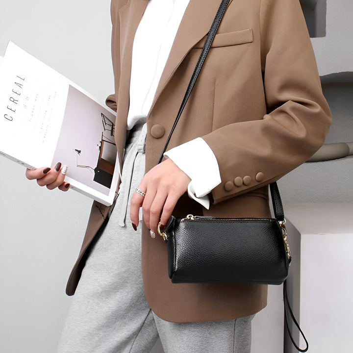 Sac bandoulière en cuir noir porté par femme en blazer marron., 46266441924832,46266441957600,46266441990368