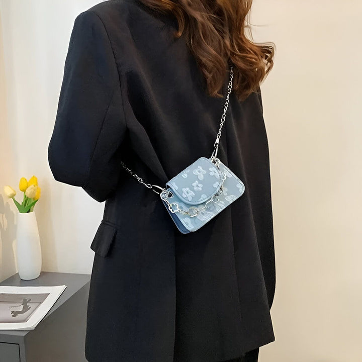 Sac bandoulière bleu clair à motif floral et chaîne argentée porté par une femme., 46193968414944,46193968447712,46193968480480,46193968513248,46193968546016