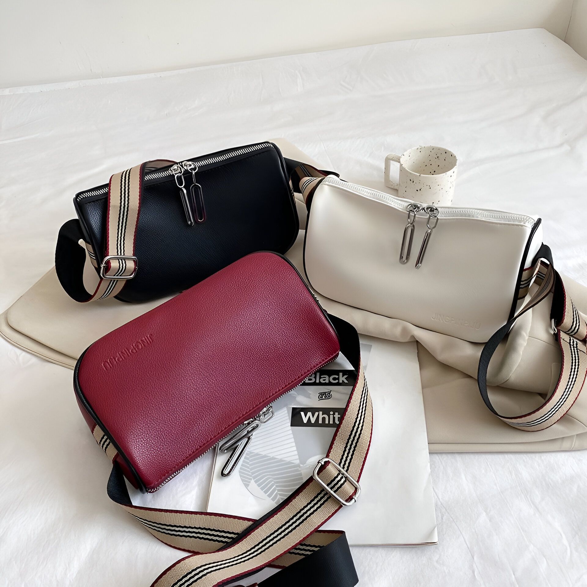 Trois sacs à main de couleur noire, blanche et rouge avec des sangles noires et blanches.