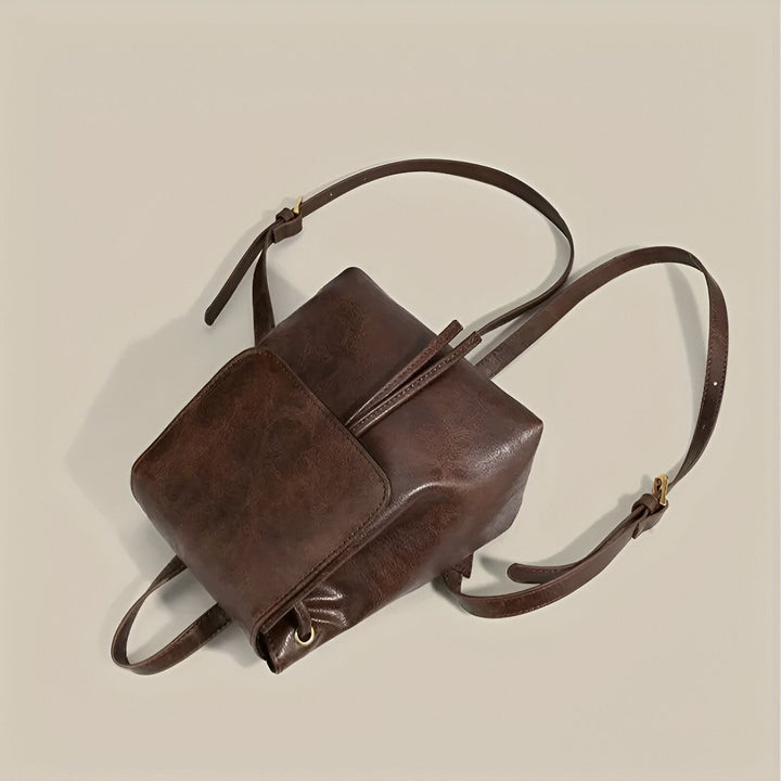 Sac à dos marron en cuir avec rabat et bretelles sur fond clair., 46194001805536,46194001838304