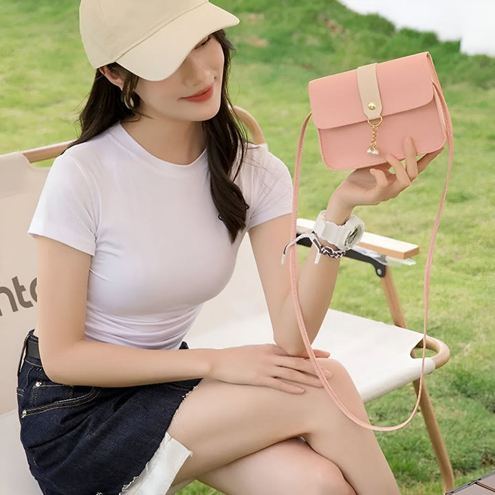 Femme avec casquette tenant un petit sac rose assise dehors., 46262754246880,46262754279648,46262754312416,46262754345184,46262754377952