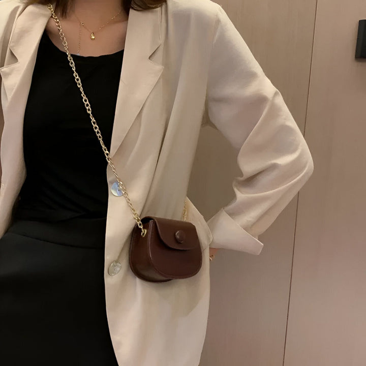 Personne portant un blazer crème, une tenue noire et un mini sac marron avec chaîne dorée., 46193969856736,46193969889504,46193969922272,46193969955040,46193969987808,46193970020576