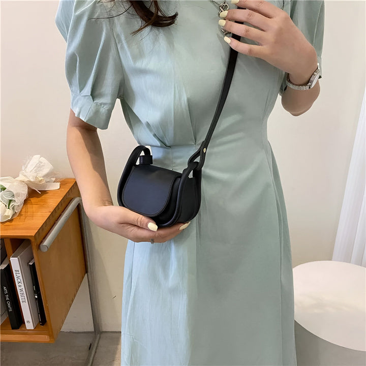 Femme en robe verte pâle tenant un petit sac noir à bandoulière., 46193971232992,46193971265760,46193971298528,46193971364064,46193971396832