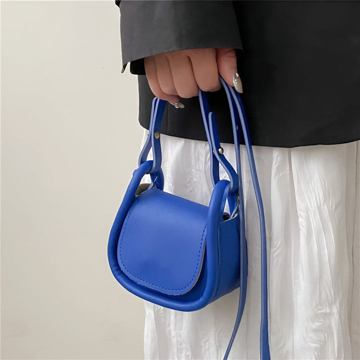Petite sacoche bleue portée à la main par une personne., 46193971232992,46193971265760,46193971298528,46193971364064,46193971396832