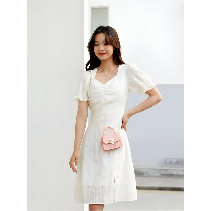 Femme en robe blanche à manches bouffantes et sac cœur rose., 46262992208096,46262992240864,46262992273632,46262992339168,46262992371936,46262992404704,46262992437472