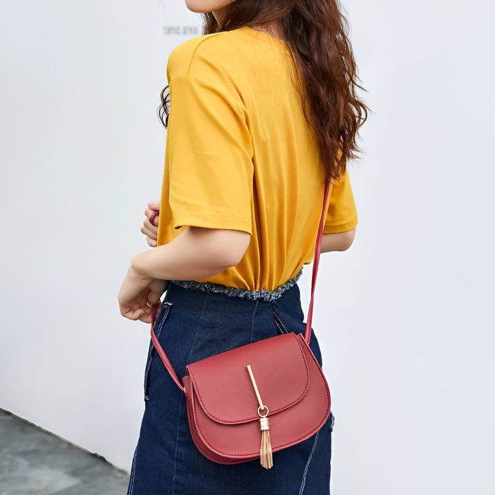 Sac rouge à bandoulière avec pompon doré porté par une femme, 46262994567392,46262994600160,46262994632928,46262994665696,46262994698464,46262994731232