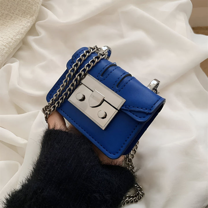 Petit sac bleu tenu par une main, avec chaîne et fermoir argentés., 46193972642016,46193972674784,46193972707552,46193972740320,46193972773088,46193972805856