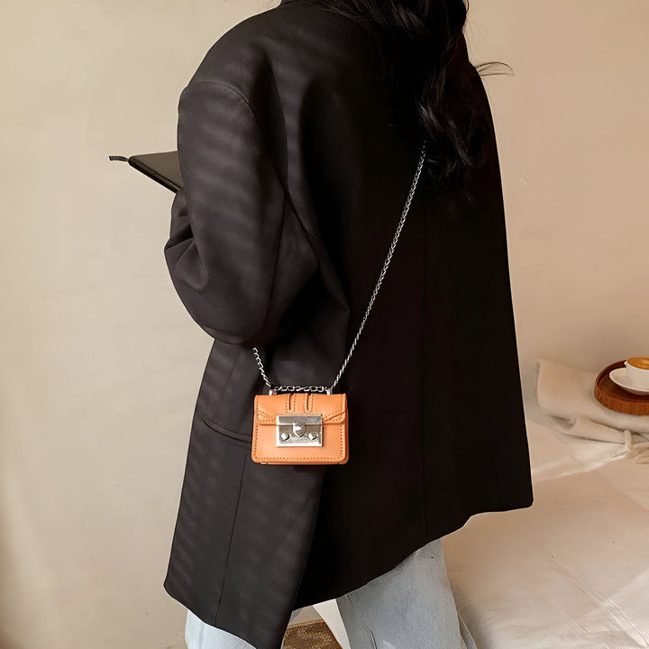 Personne de dos en blazer noir et jean, portant un mini sac orange à chaîne argentée., 46193972642016,46193972674784,46193972707552,46193972740320,46193972773088,46193972805856