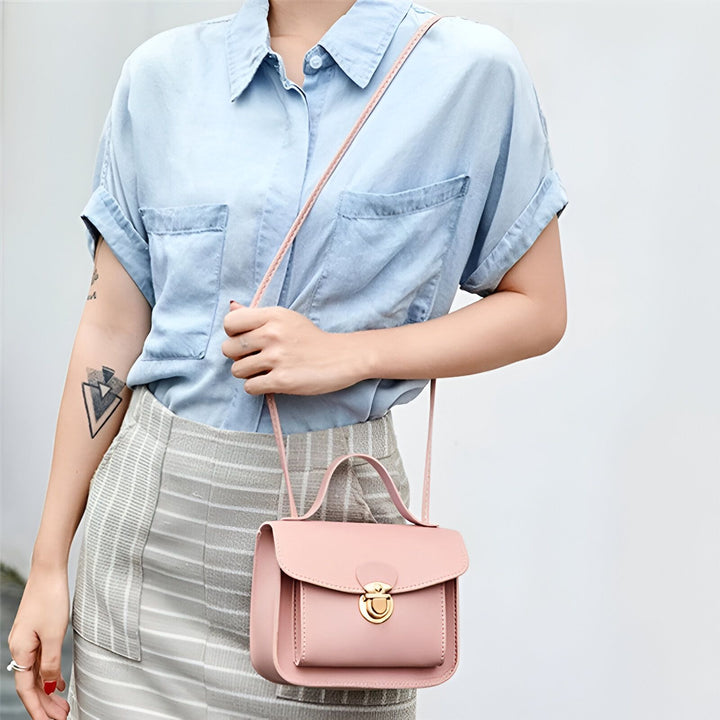 Femme portant un petit sac à main rose en bandoulière, une chemise bleue et une jupe rayée grise., 46262767386848,46262767419616,46262767452384,46262767485152,46262767517920