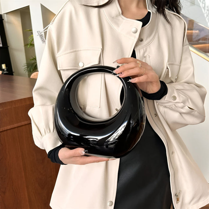 Femme tenant un sac à main noir brillant, ovale avec un trou circulaire., 46194015502560,46194015535328,46194015568096,46194015600864,46194015633632,46194015666400