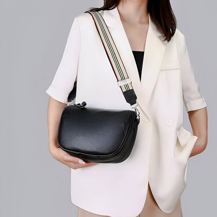 Femme tenant un sac bandoulière noir en cuir avec anse rayée., 46262995747040,46262995779808,46262995812576,46262995845344