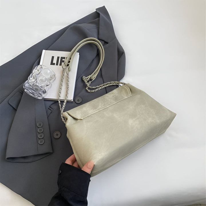 Sac à main gris clair texturé avec anse chaîne, posé sur un blazer gris foncé, tenu par une main., 46193885544672,46193885577440,46193885610208,46193885642976