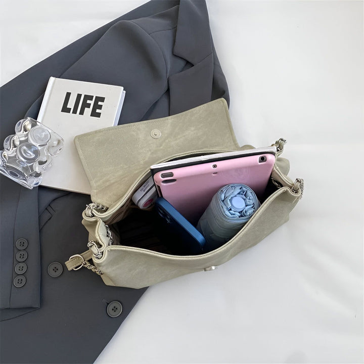Sac à main vert clair ouvert avec tablette rose, téléphone bleu et parapluie bleu sur un blazer gris., 46193885544672,46193885577440,46193885610208,46193885642976