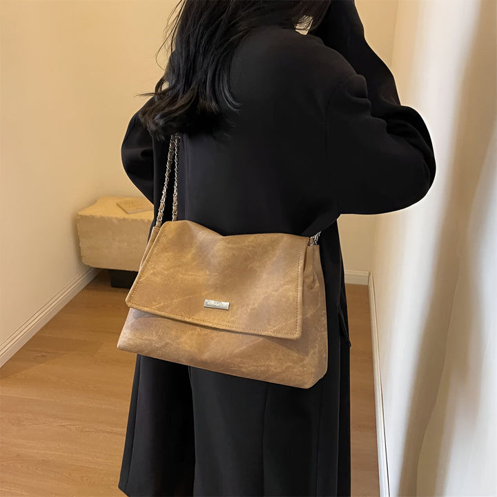 Sac bandoulière taupe avec chaîne porté par une femme en manteau noir, 46193885544672,46193885577440,46193885610208,46193885642976