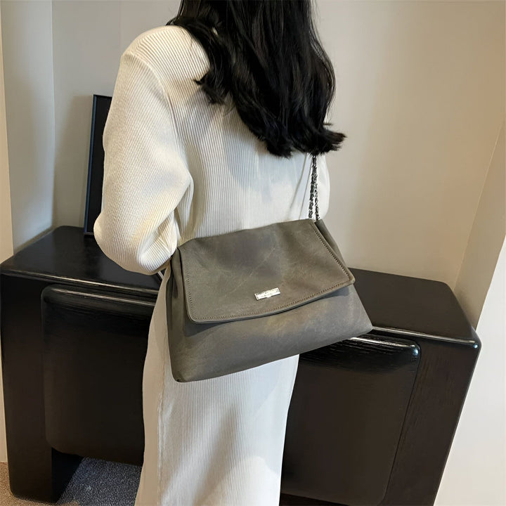 Femme en robe blanche côtelée portant un sac épaule gris avec chaîne et détail argenté., 46193885544672,46193885577440,46193885610208,46193885642976