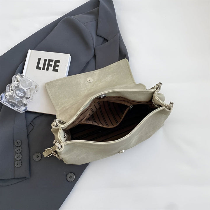 Sac à main gris clair ouvert avec anse chaîne, intérieur rayé, posé sur un blazer., 46193885544672,46193885577440,46193885610208,46193885642976