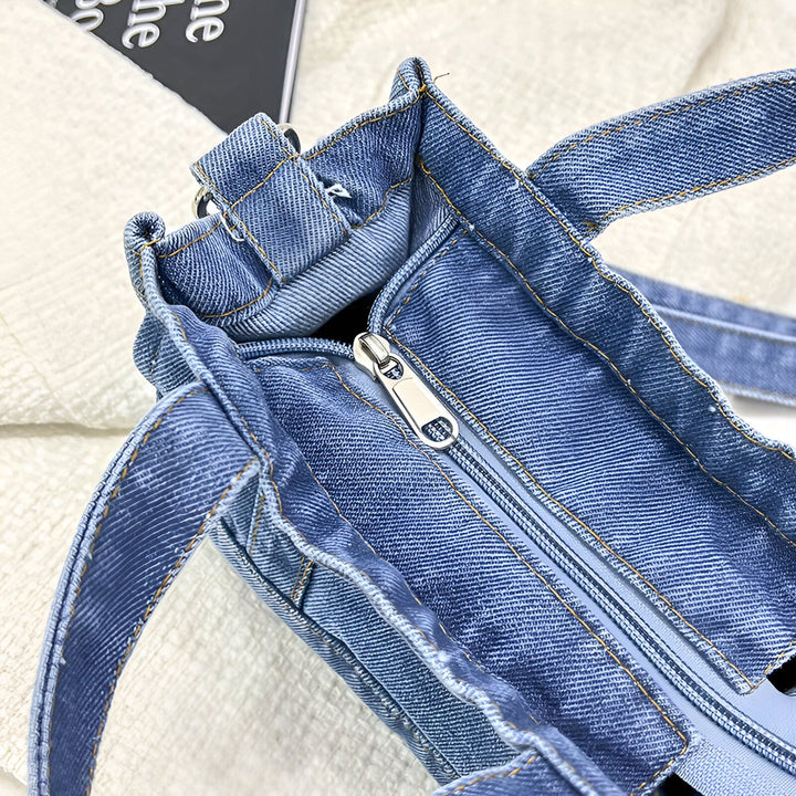 Sac fourre-tout en jean bleu avec fermeture éclair argentée et coutures apparentes., 46193993285856,46193993318624
