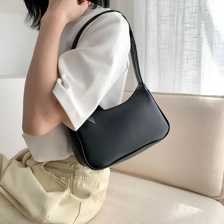 Sac baguette noir porté à l'épaule par une personne., 46193965596896,46193965629664,46193965662432,46193965695200,46193965727968,46193965760736,46193965793504
