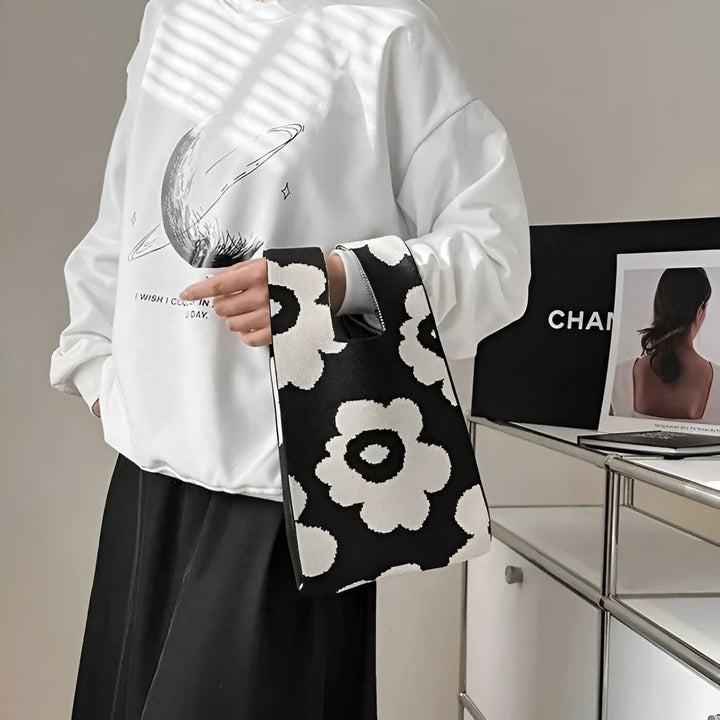 Personne portant un haut blanc et une jupe noire tenant un sac cabas noir et blanc à motif floral., 46193944363232,46193944396000,46193944428768