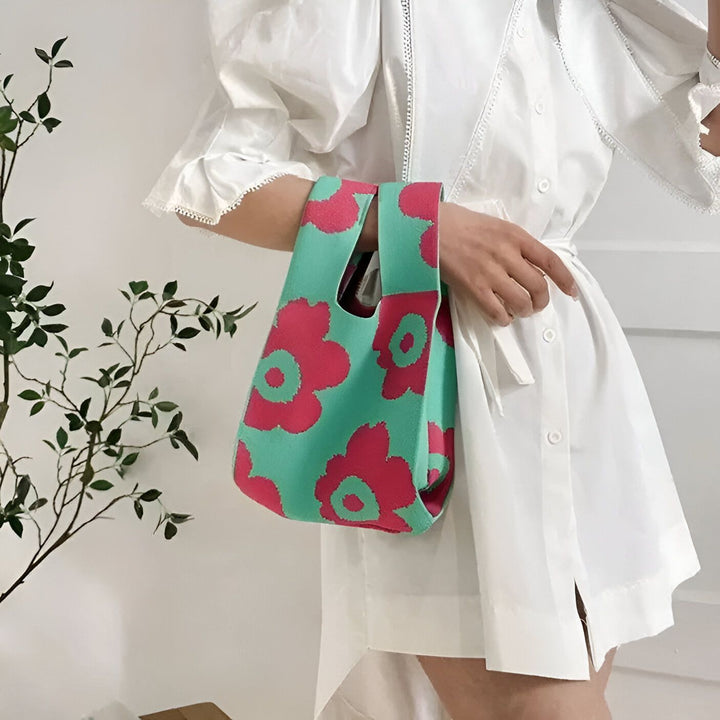 Femme en robe blanche tenant un petit sac tricoté floral rose et vert., 46193944363232,46193944396000,46193944428768