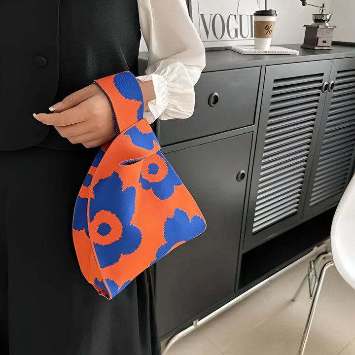 Personne tenant un sac fourre-tout orange et bleu à motifs floraux., 46193944363232,46193944396000,46193944428768