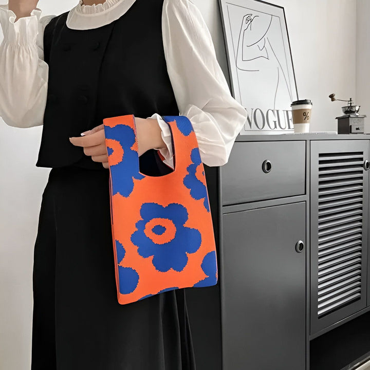 Personne tenant un petit sac orange et bleu à motifs floraux., 46193944363232,46193944396000,46193944428768