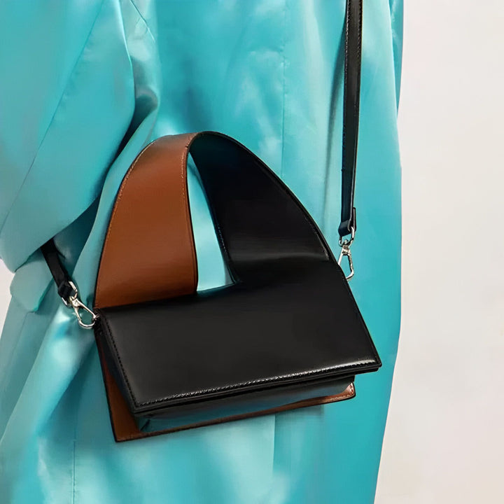 Gros plan sur un sac à main noir anse marron porté avec un vêtement bleu sarcelle., 46194016420064