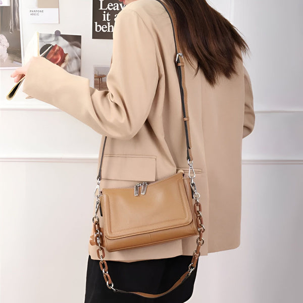 Sac bandoulière en cuir camel avec chaîne porté par femme en blazer beige., 46193851498720