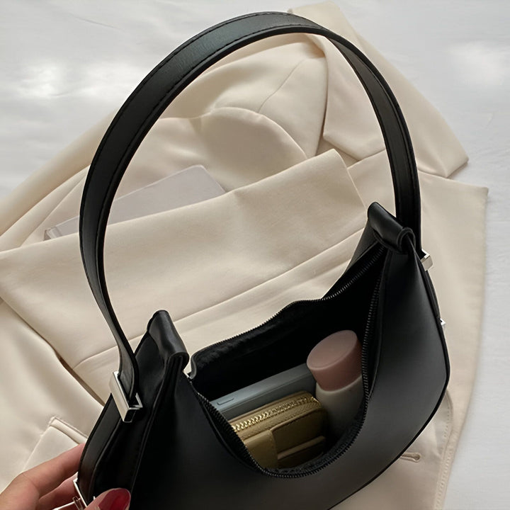 Sac à bandoulière noir ouvert avec téléphone et porte-monnaie à l'intérieur, posé sur une veste beige., 46193940398304,46193940463840,46193940496608,46193940529376
