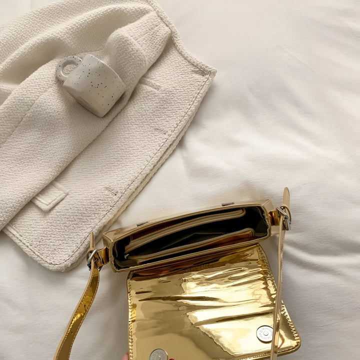 Sac bandoulière doré ouvert, veste blanche texturée et petite tasse., 46194032705760