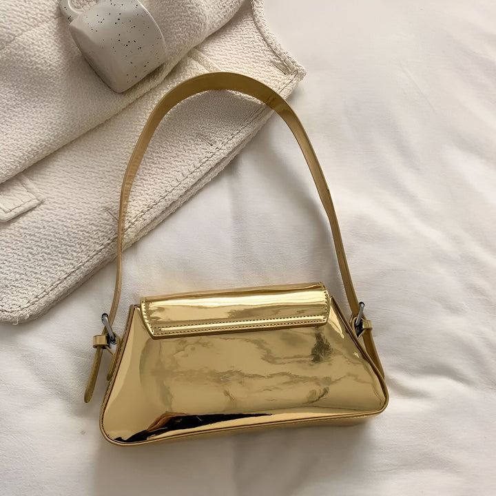 Petit sac à main doré brillant avec bandoulière sur un fond blanc, 46194032705760